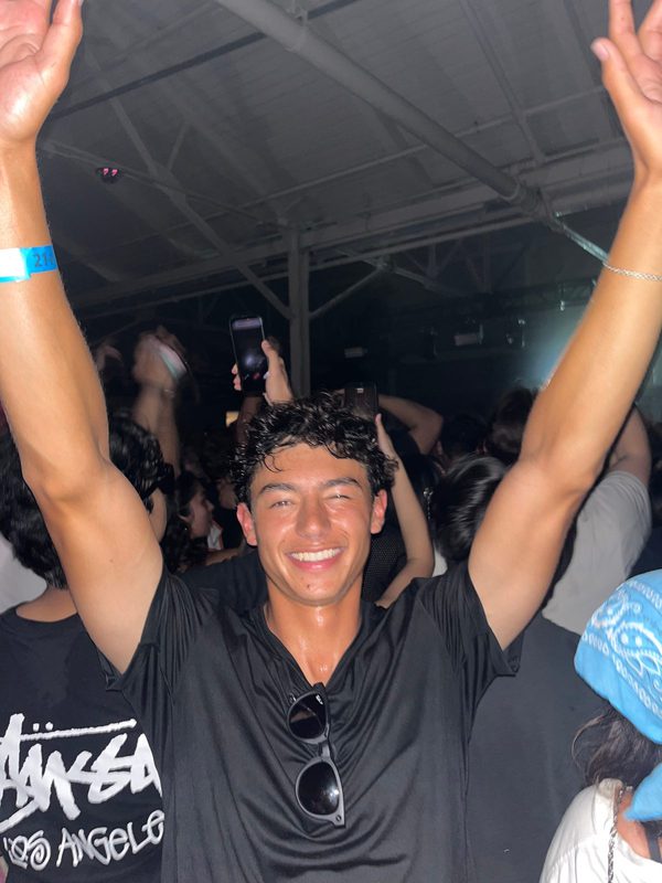 Felipe with his arms up in the crowd at an electronic music show